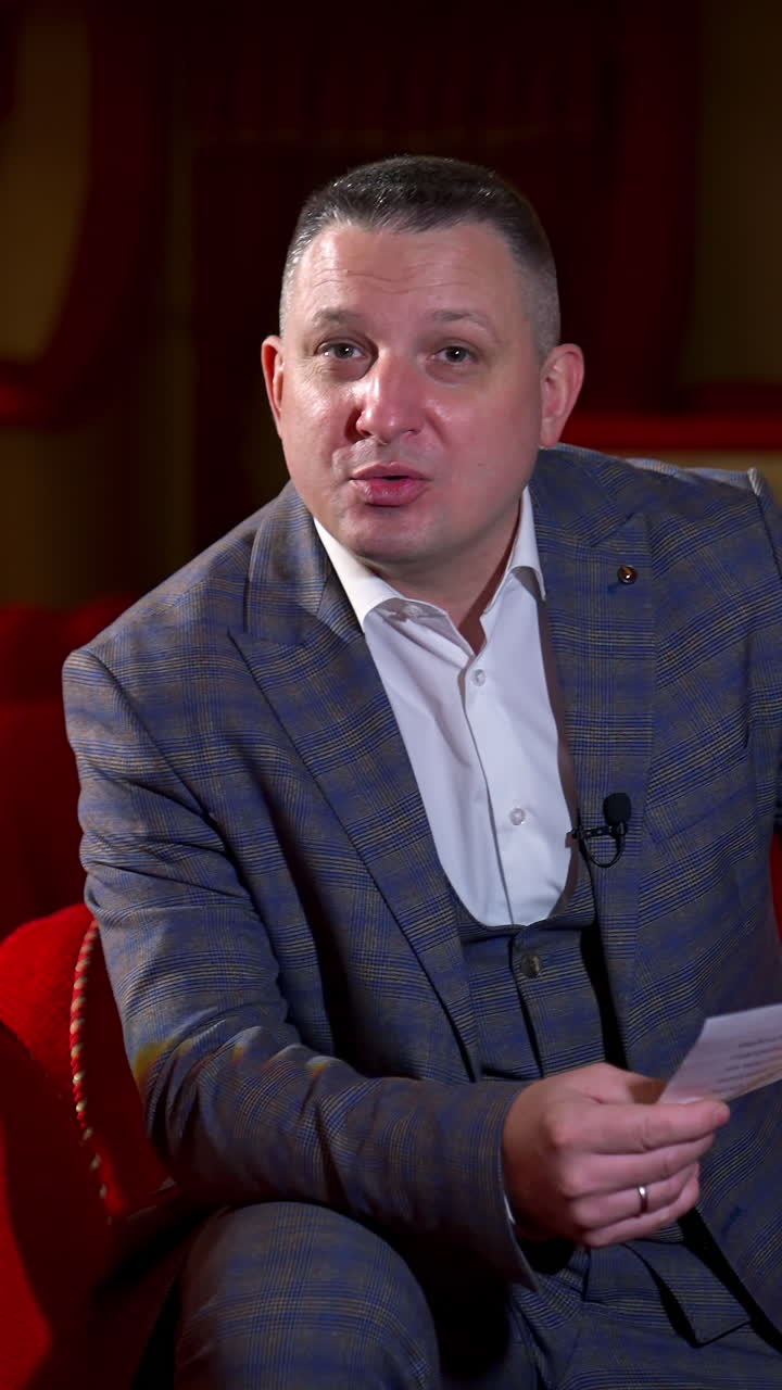 Actor at rehearsal in auditorium. Man repeating monologue while sitting among red chairs in the empty hall. Speaker rehearsing before the performance. Vertical video