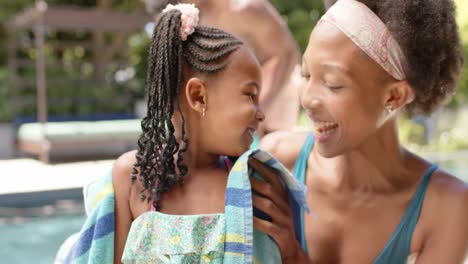 feliz madre afroamericana toallando a su hija en la piscina, en cámara lenta