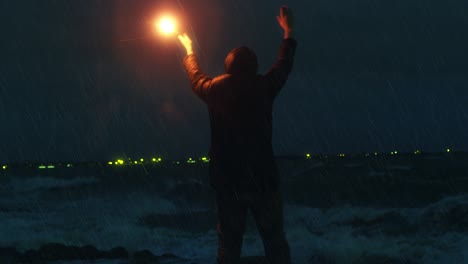 hombre saludando con una torcha de señal de carretera para pedir ayuda en una tormenta