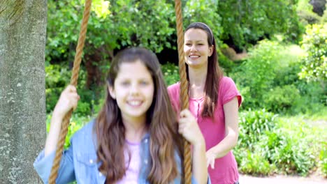 mother pushing her daughter on a swing