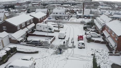 Una-Familia-Raspa-La-Nieve-Y-El-Hielo-De-Su-Camino-De-Entrada-Y-De-La-Carretera-Después-De-Una-Fuerte-Nevada,-Ventisca-En-La-Región-De-West-Midlands,-Longton,-Stoke-On-Trent,-Staffordshire