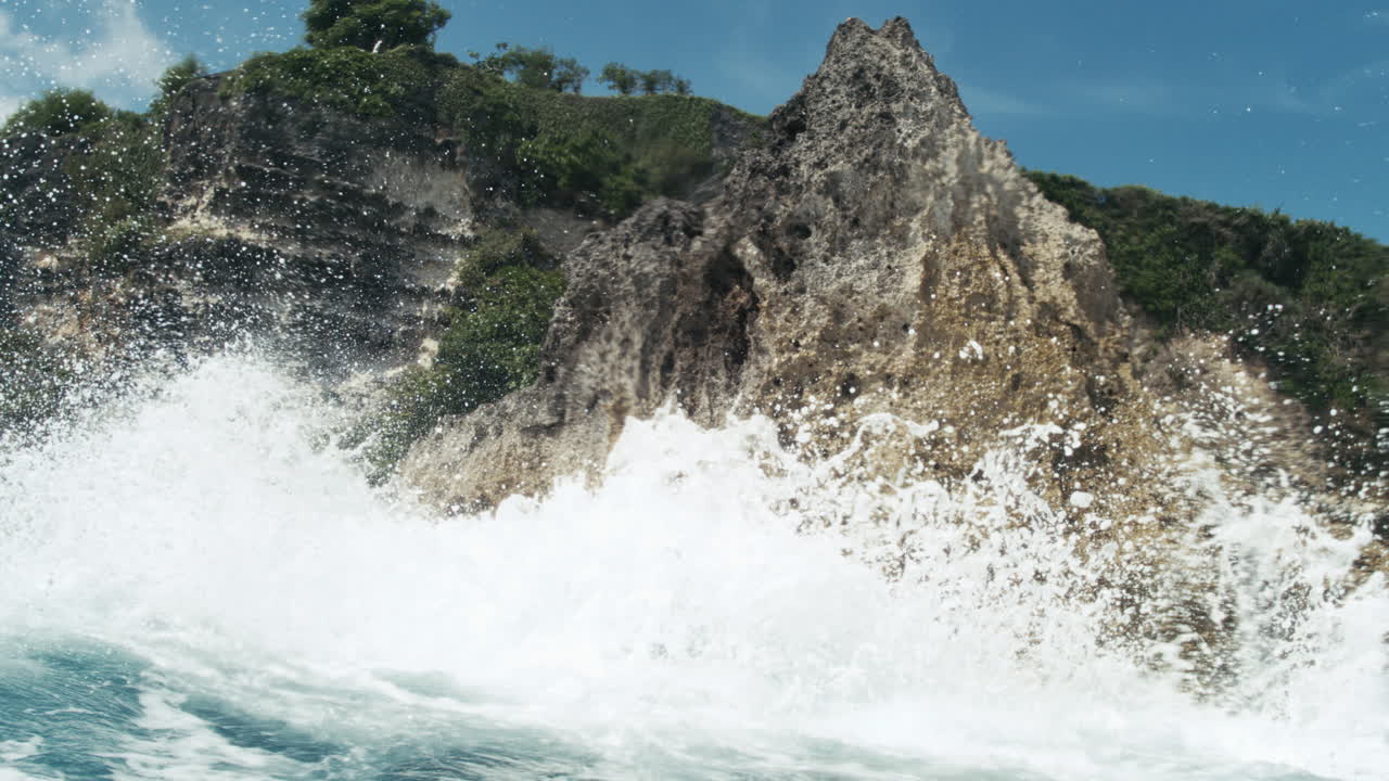 Whitewater churns violently at the base of a craggy cliff face, slow motion slowmo backdrop