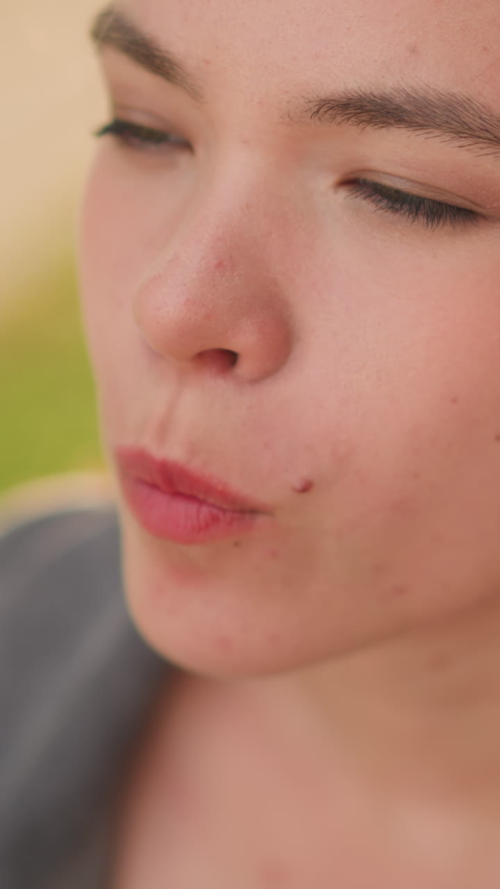 primer plano de una dama disfrutando de shawarma al aire libre, centrándose en su mano sosteniendo el bocadillo y el momento de comer, fondo verde borroso con suave luz del día