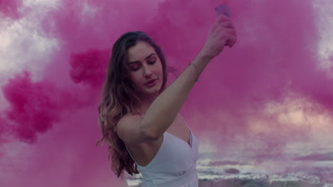 Hermosa-Mujer-Agitando-Una-Granada-De-Humo-Rosa-Bailando-En-La-Playa-Temprano-En-La-Mañana-Celebrando-La-Libertad-Creativa