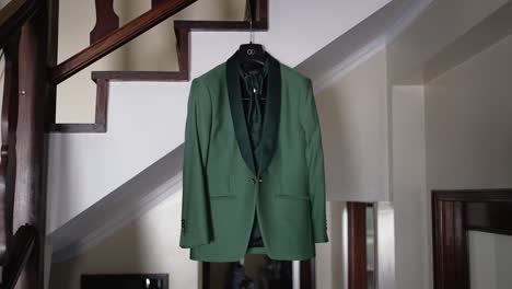 green formal suit hangs neatly in hallway before wedding ceremony indoors