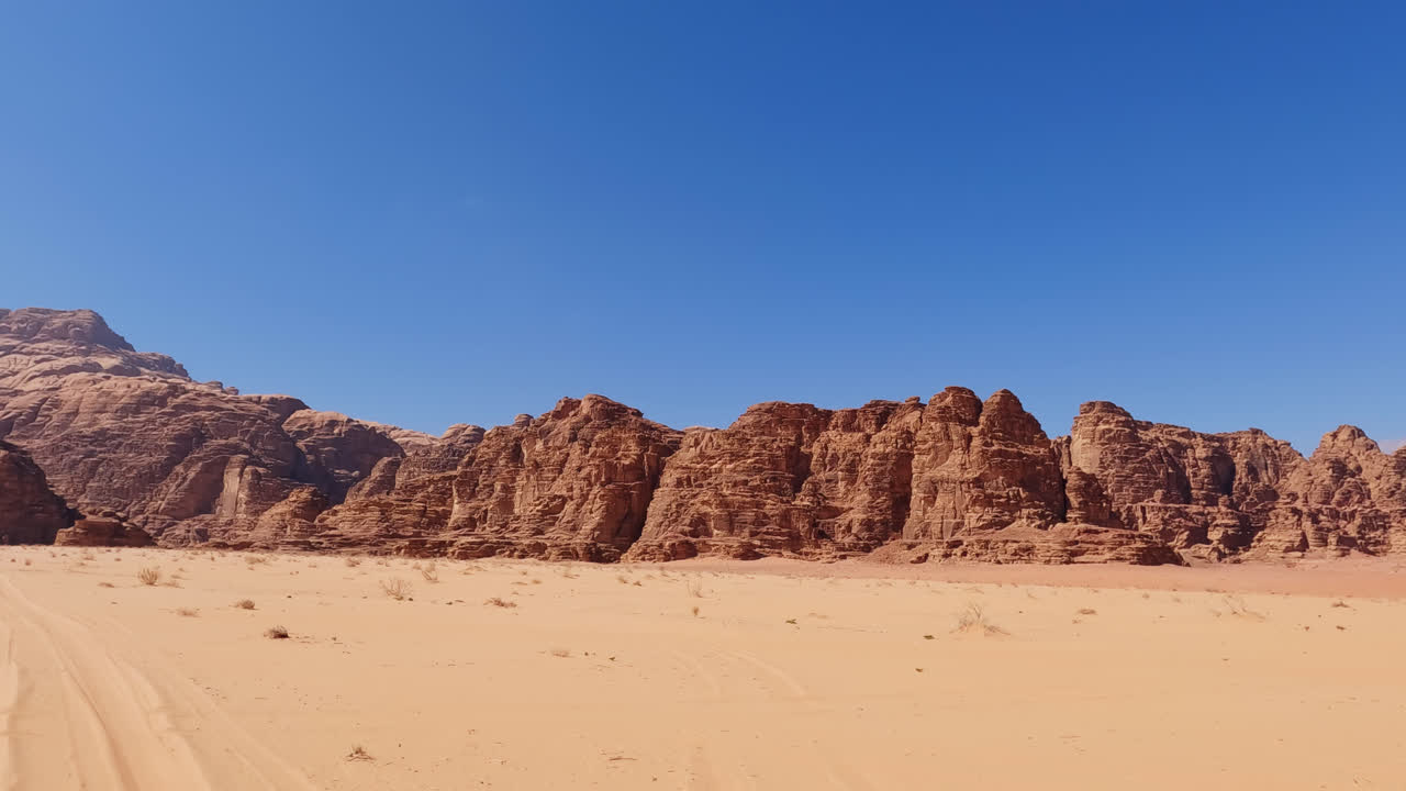 Langit biru cerah di atas tebing punggung bukit yang megah dari pemandangan Wadi Rum.