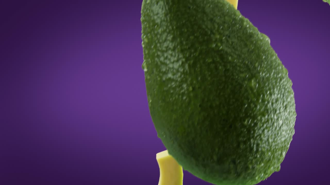 aguacate con rebanadas que caen sobre un fondo púrpura