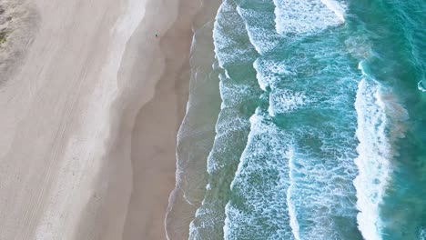 waves crashing on sandy shore from above