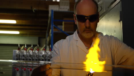 front view of mature male worker blowing glass in glass factory 4k