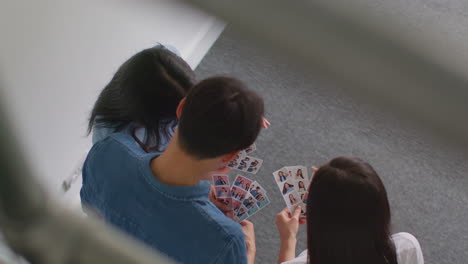 looking down on group of friends having fun looking at prints from photo booth 2