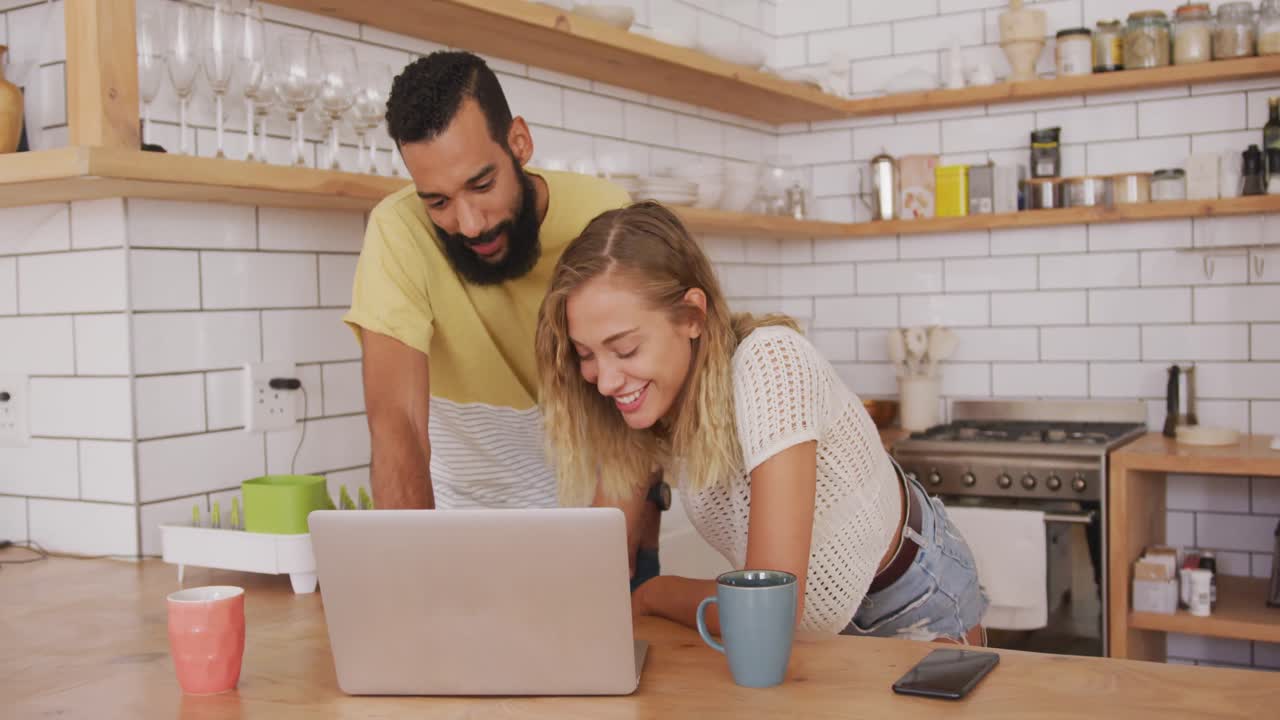 pareja feliz sonriendo mientras usa una computadora portátil en casa
