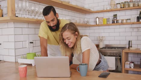 Happy-couple-smiling-while-using-laptop-at-home