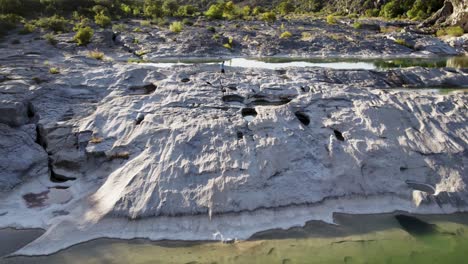 Drohne-Verfolgt-Person,-Die-Bei-Sonnenuntergang-über-Felsen-Und-Wasser-Im-State-Park-Läuft