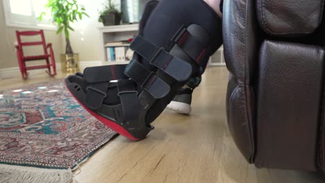 senior man with an ankle injury struggles to put on an orthopedic boot