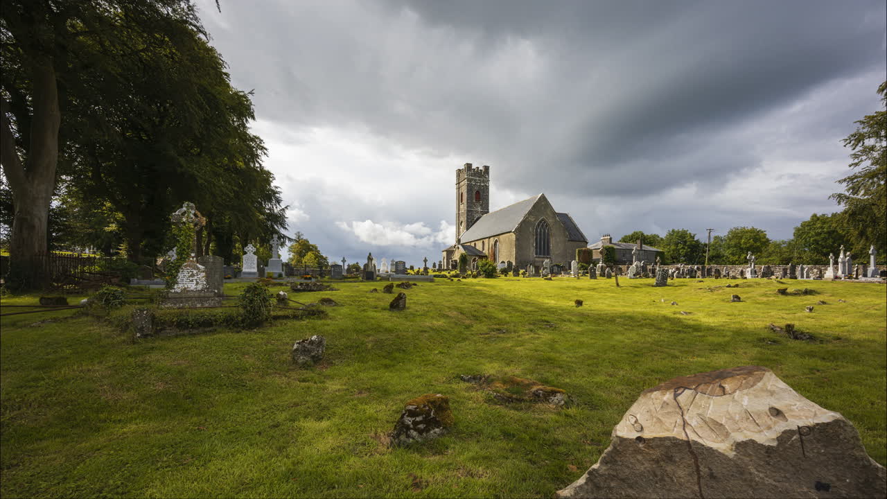 lapso de tiempo del cementerio histórico y la iglesia medieval en la irlanda rural con nubes pasajeras y sol