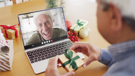 biracial man with santa hat having laptop video call with caucasian man