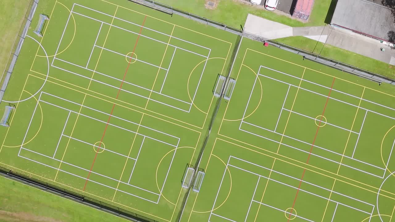 Drone footage showcasing green sports courts with clear boundary lines and surrounding pathways.