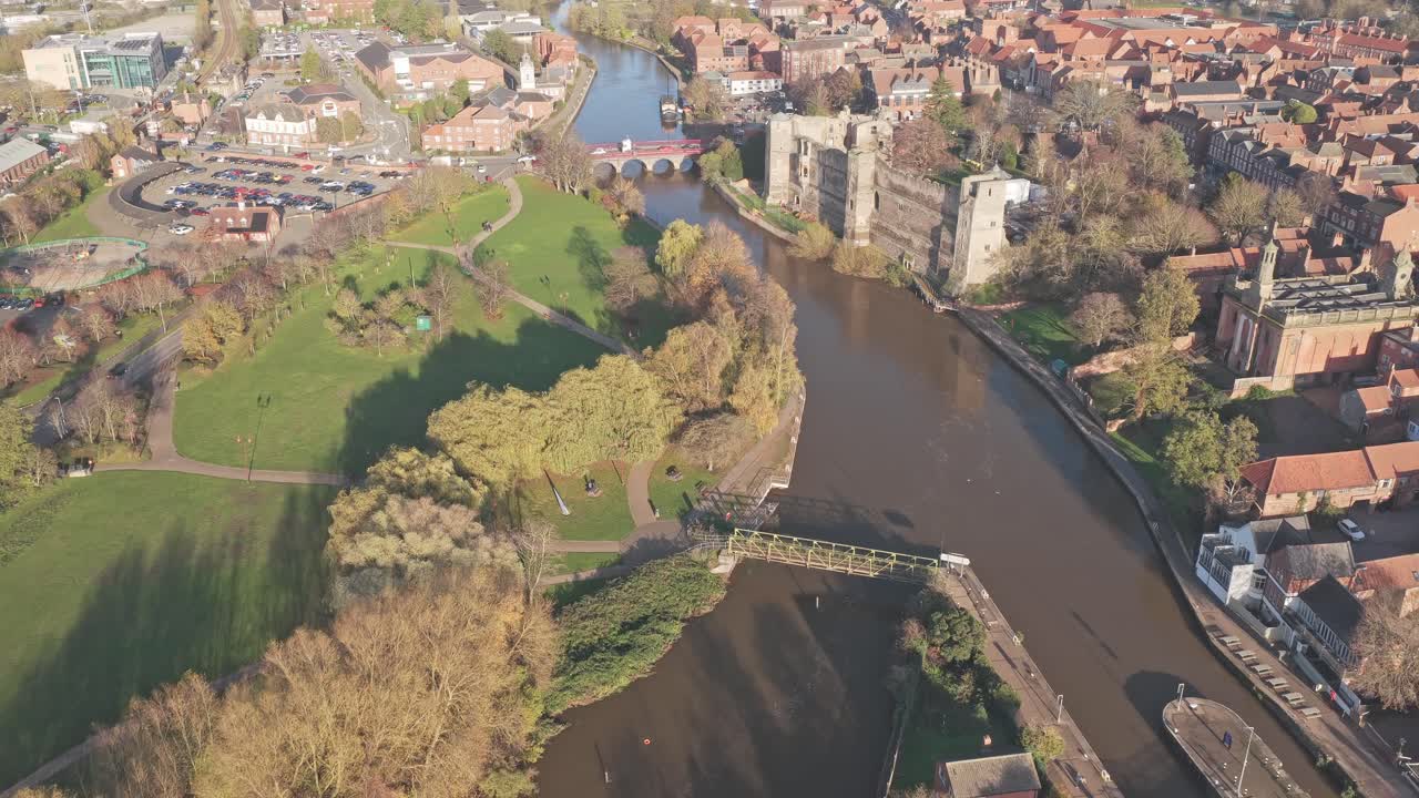 Newark on Trent townscape from aerial view, showing a historic castle, town buildings, River Trent, and lush green parkland in Nottinghamshire, England during autumn