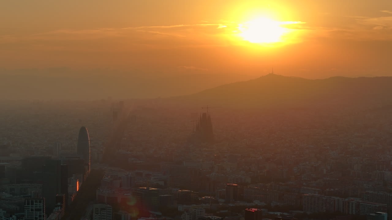 Aerial drone view of Barcelona city at sunset with orange sun