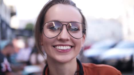 magnífica vista de cerca de una joven rubia mirando a la cámara y sonriendo, con unas gafas elegantes y modernas. feliz