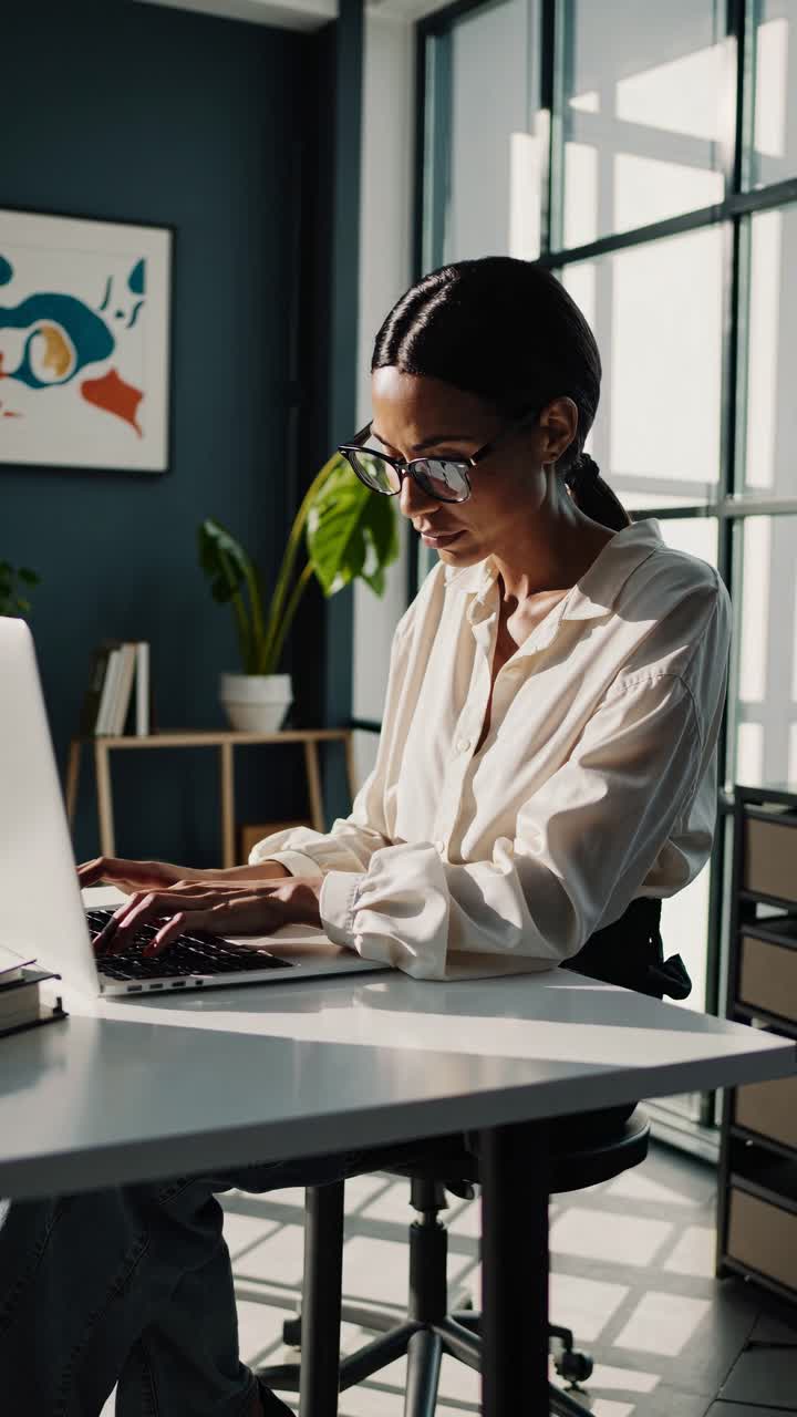 A professional woman works on a laptop in a modern office