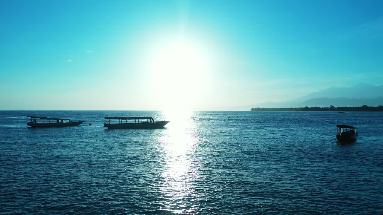 열대 섬을 여행하기 위해 관광객들이 승선하기를 기다리는 정박된 보트로 가득 찬 잔잔한 석호에 태양이 반사되면서 일출의 빛나는 바다 풍경