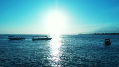 Glowing-seascape-at-sunrise-with-sun-reflecting-on-calm-lagoon-full-of-anchored-boats-waiting-for-tourists-to-come-on-board-for-traveling-around-tropical-islands