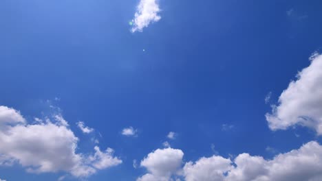 loop features of puffy fluffy white clouds floating in blue sky, beautiful sun glare, rotating video, 4k, slow motion.