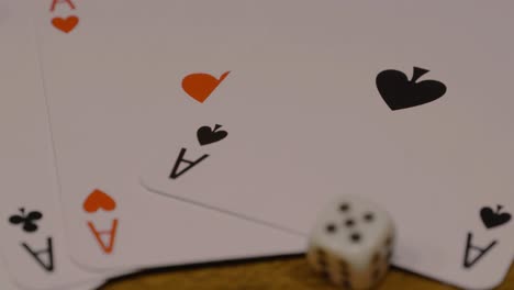 slow dolly in shot of poker cards with ace of spades in red and black with dice on a wooden table