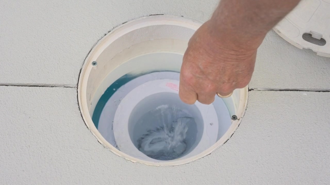 Inserting a Chlorine tablet into the pool filter for maintenance.