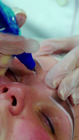 cosmetologist applying permanent make up on eyebrows
