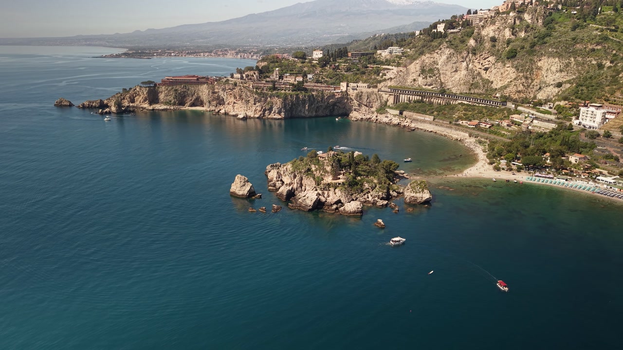 Isola Bella island Birdseye aerial view tilt up to reveal Mount Etna Italian horizon