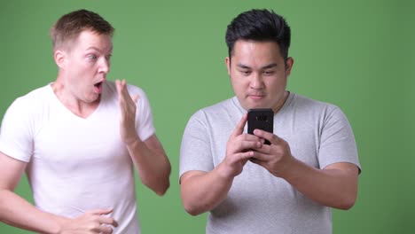 two young multi-ethnic handsome men together against green background