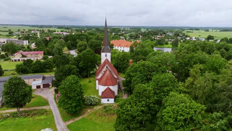 lutheran church with red roof stands in lush jaunpils surrounded by countryside
