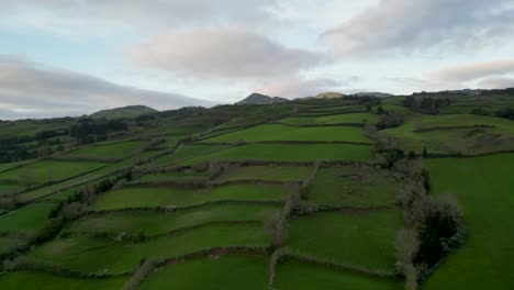 Vista-Aérea-Giratoria-De-Paisajes-En-Cascada-En-Azores,-Portugal,-Que-Retrata-Actividades-Agrícolas.