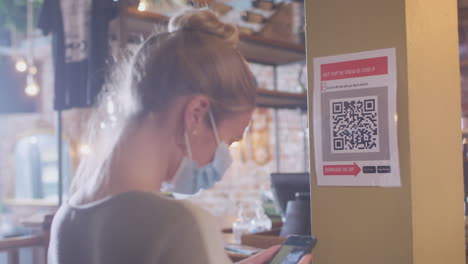 Frau-Mit-Maske-Und-Mobiltelefon-Checkt-Während-Einer-Gesundheitspandemie-In-Den-Veranstaltungsort-Ein-Und-Scannt-Den-QR-Code