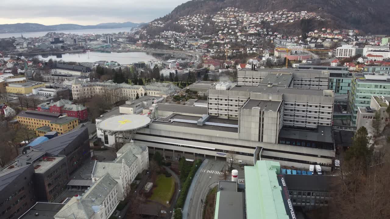 hospital de haukeland con la ciudad de bergen en el fondo - antena en movimiento hacia arriba cerca de los edificios del hospital con fondo de paisaje urbano - noruega
