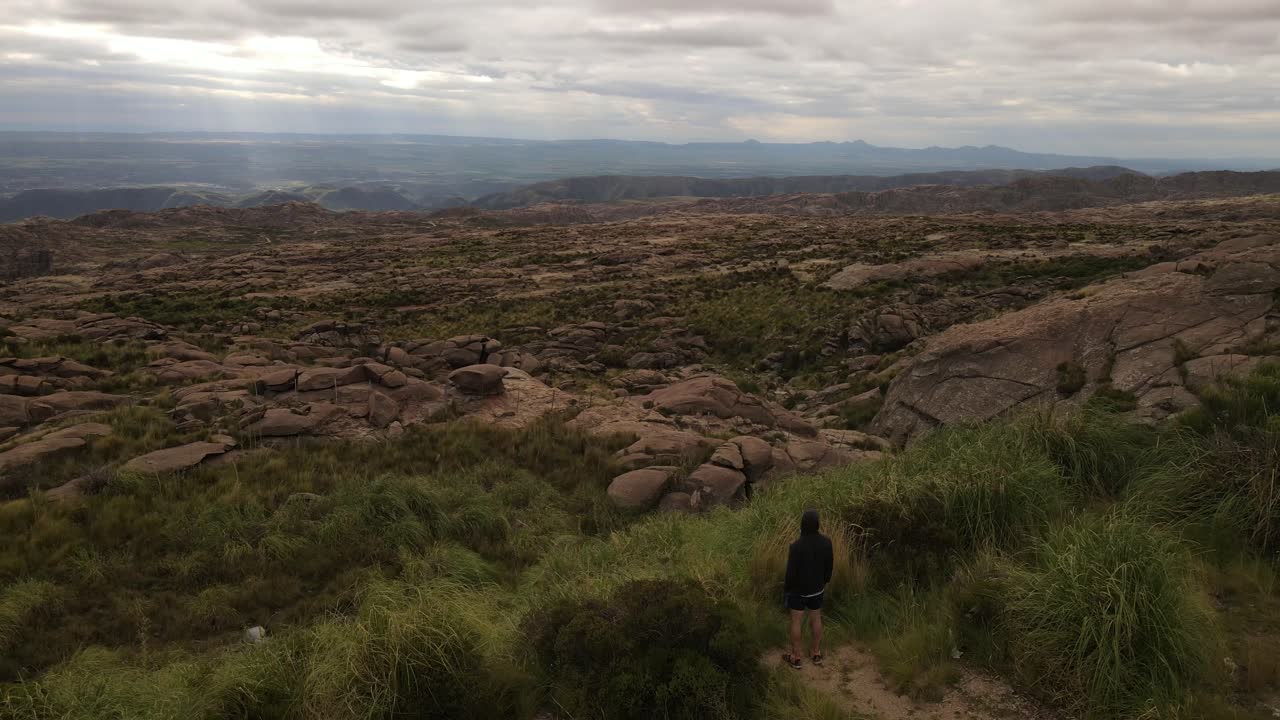 toma de órbita aérea de un joven frente a las tierras altas disfrutando de una vista panorámica de la naturaleza - argentina, sudamérica