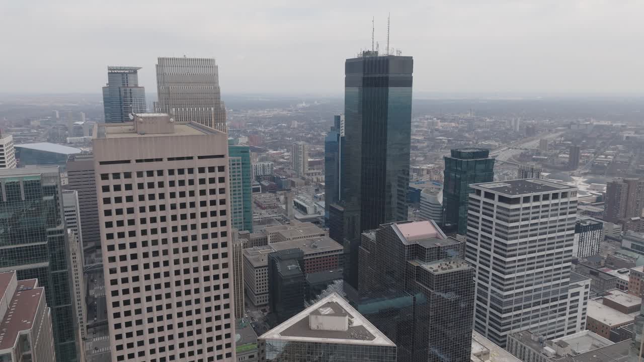 Drone footage of Minneapolis skyline with IDS Center and cityscape below.