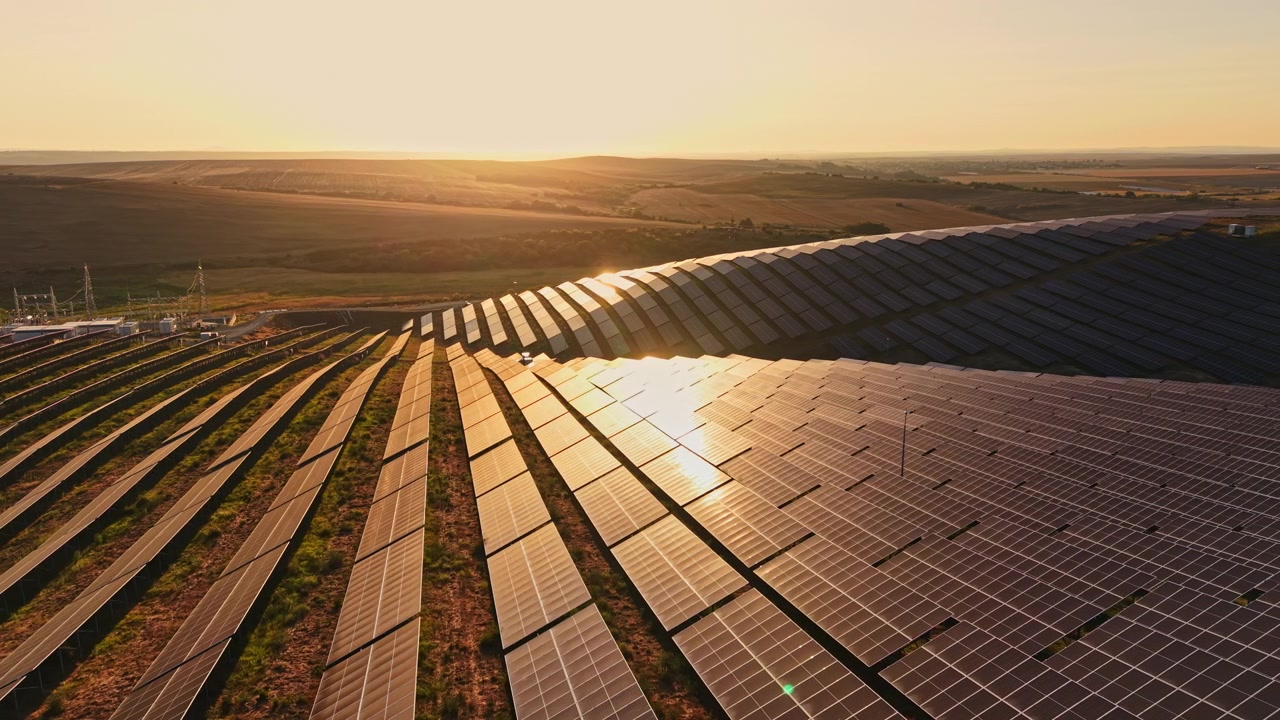 Solpaneler dækker et stort felt i et landområde ved solnedgang