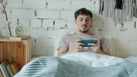 man using smartphone in bed