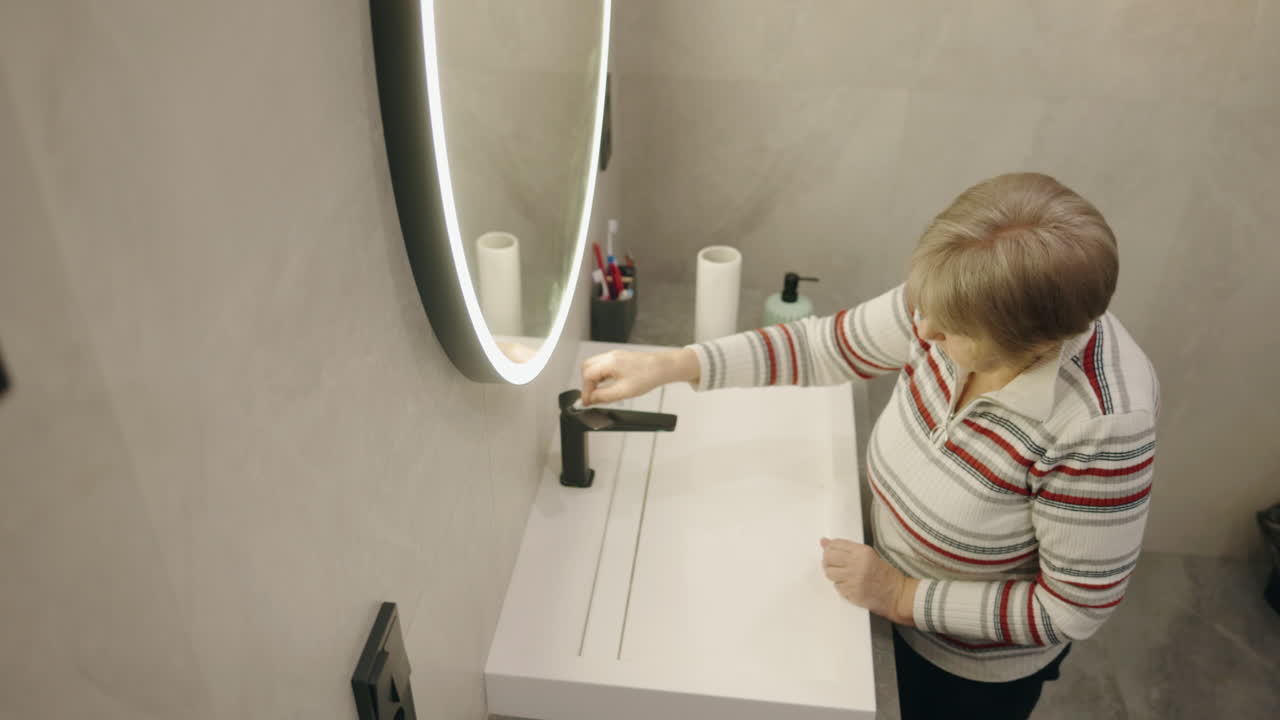 Donna anziana che si lava le mani in un bagno moderno