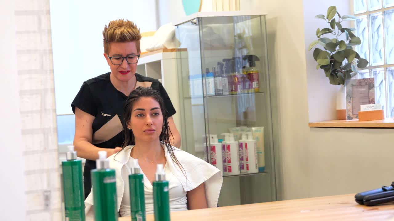 Frisør styler kundens hår i salonen