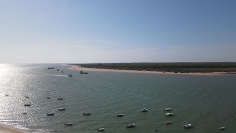 drone footage of bonanza beach, at the mouth of the guadalquivir river. there are small fishing boats on the shore and in the background you can see the doñana natural park.