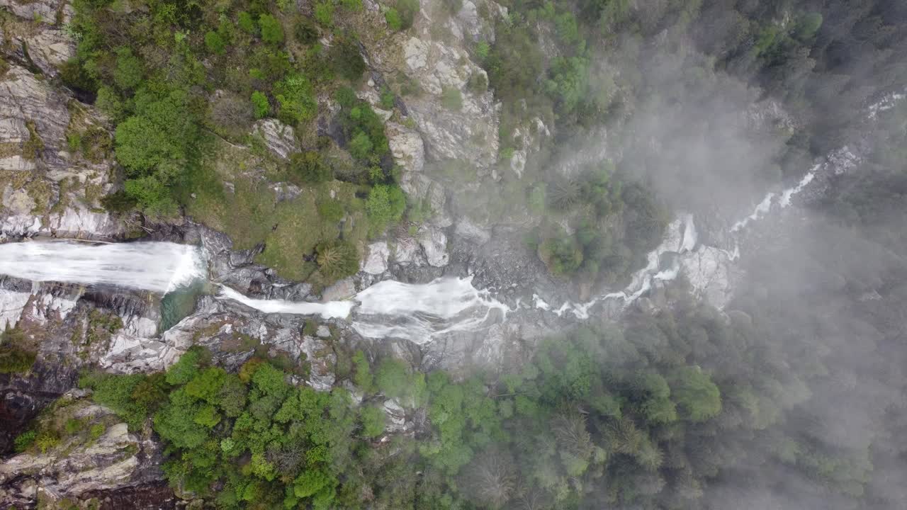 vista aérea de arriba hacia abajo de una poderosa cascada que cae en cascada a través de las rocas y los pinos - valle d'aosta, gressoney-saint-jean