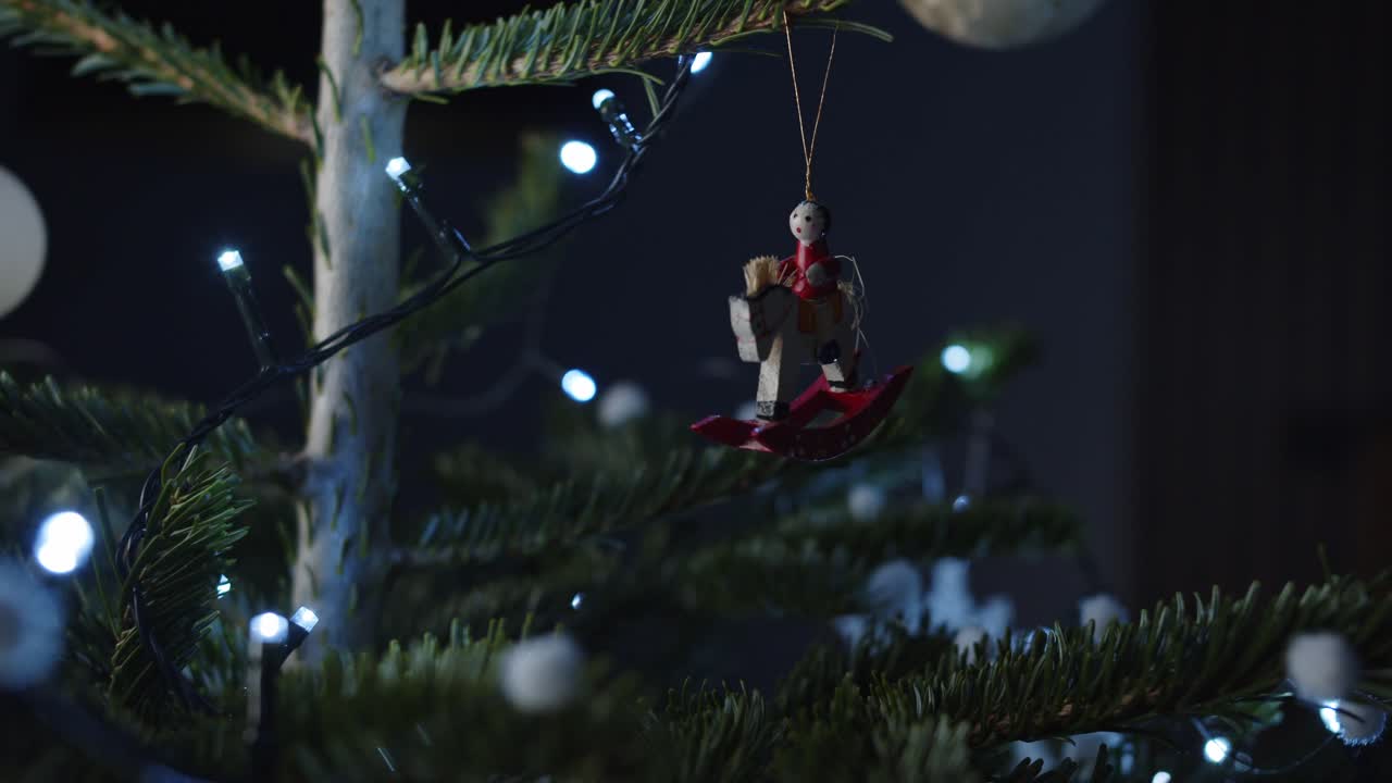 A festive wooden ornament hangs amidst twinkling Christmas tree lights and branches