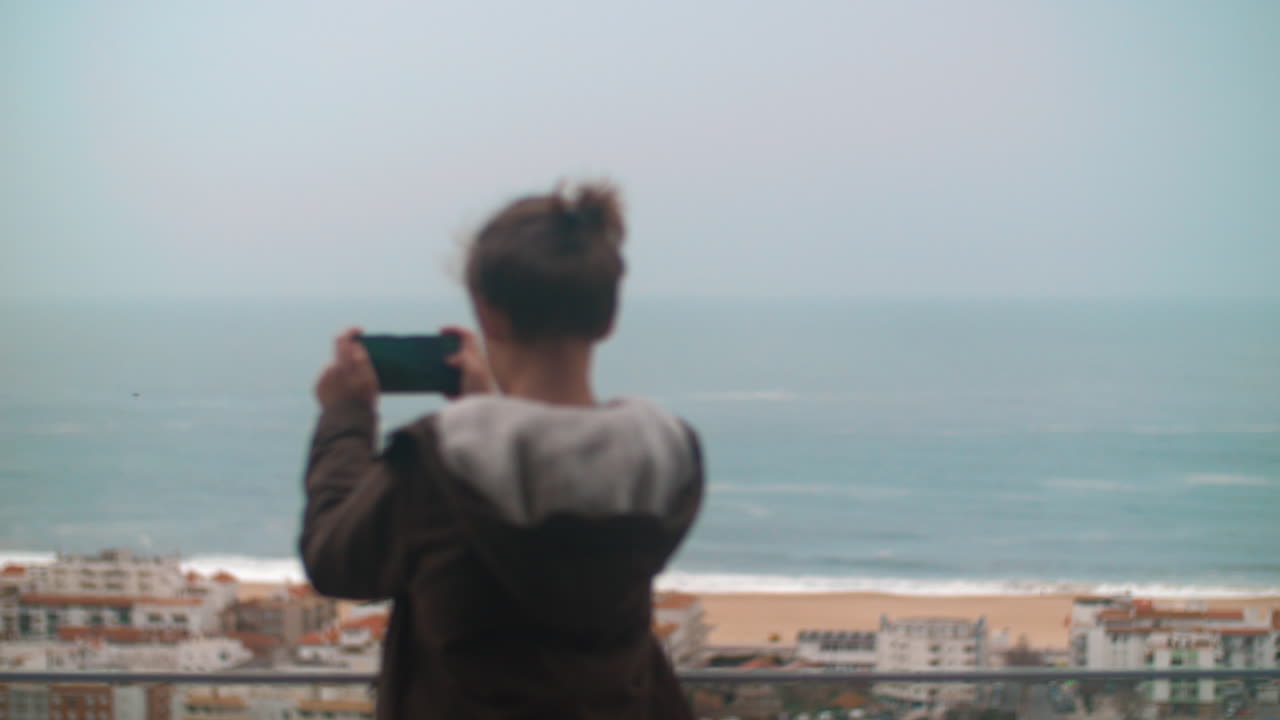 아이가 포르투갈 나자레에서 바다 해안의 풍경 사진을 찍고 있습니다.