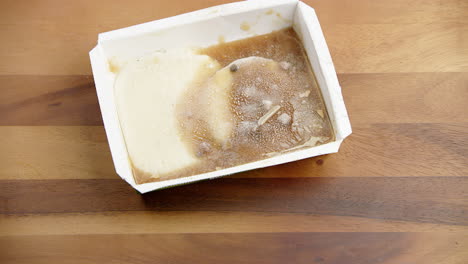 Deep-frozen-snack-food-meal-box-being-thrown-on-a-wooden-dining-table