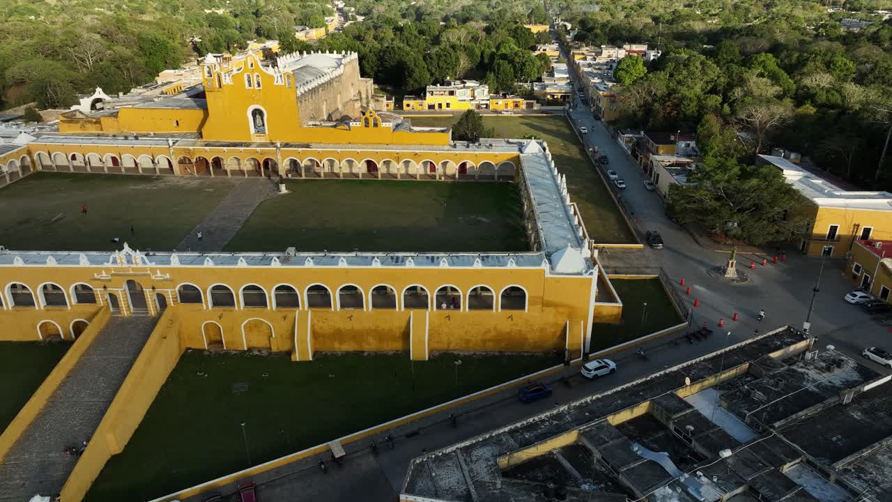 Side-to-side aerial traveling over the San Antonio de Padua ex-convent in Izamal, Yucatán, Mexico. The drone moves right to left, revealing the yellow arcades, large atrium and the surrounding town