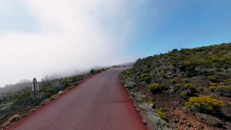 atmospheric drone footage capturing a car winding through misty mountain roads in reunion island. dramatic fog creates mystical scenery in this french territory.